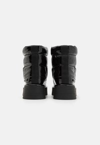 Black patent leather ankle boots with a quilted design, featuring a chunky rubber sole and fabric accents on the back.