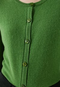 Zielony sweter z dzianiny z okrągłym dekoltem, sześcioma dopasowanymi guzikami oraz teksturowanym przodem z guzikami. Miękki materiał o gładkim wykończeniu.
