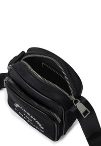 Borsa a spalla nera realizzata in nylon resistente, con numerosi scomparti con cerniera, dotata di hardware in metallo argentato e di un logo bianco a contrasto sul davanti.