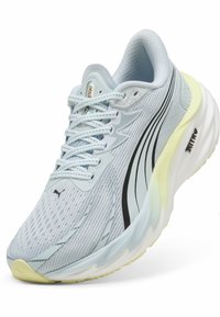 Shoe desportivo azul-claro com parte superior em malha, detalhes em preto e palmilhas brancas espessas. Apresenta uma superfície texturizada e um design de bico arredondado.