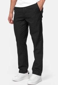 Zwarte katoenen broek met een rechte pijpdesign, voorzien van zijzakken en een soepele textuur, gecombineerd met witte sneakers.