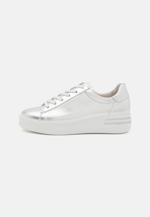 Sneaker métallisé argenté avec un bout rond, un laçage à l'avant et une épaisse semelle blanche. Texture lisse avec des coutures minimales et des accents de design subtils.
