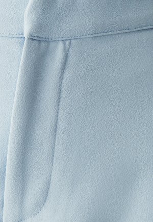 Tejido azul claro con una textura suave; presenta una costura y un detalle plegado. El material parece liviano y ligeramente texturizado.