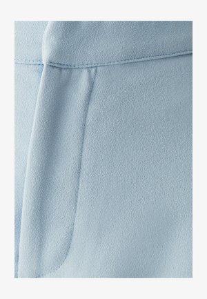 Vaaleansininen kangas, jossa on sileä rakenne; siinä on sauma ja taitettu yksityiskohta. Materiaali vaikuttaa kevyeltä ja hieman teksturoidulta.