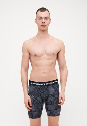 Svarte boksershorts med slangestruktur og en tykk svart midjebånd med hvit "Jordan Sport" tekst. Laget av et elastisk materiale.