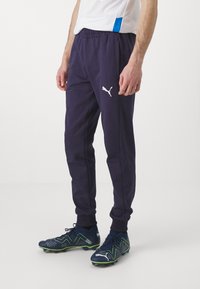 Námornícke športové nohavice vyrobené z mäkkej tkaniny, s elastickým pásom a bielym logom Puma na ľavom stehne. Úzky strih, rebrované manžety.