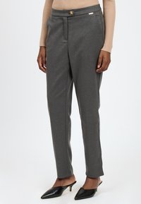 Grijze tailored broeken met een gladde textuur, voorzien van een goudkleurige knop en subtiele voor plooi, gecombineerd met zwarte puntige muilen.