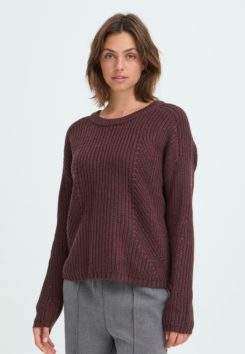 Bordeauxfarbener Strickpullover mit Rundhalsausschnitt, geripptem Textil und langen Ärmeln. Auffällige diagonale Nahtdetails am Körper.