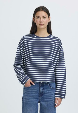 Navy and white striped long-sleeve shirt with a round neck and loose fit, made of soft fabric. Paired with blue denim jeans.