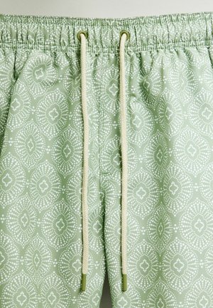 Jasnozielone szorty w wzory z elastycznym paskiem. Wzór składa się z białych kropek w diamentowym i kwiatowym wzorze.