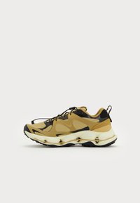 Zapatilla con parte superior de malla en tonos marrón y negro, suela curvada y tacón redondeado. Presenta cordones y una lengüeta en la parte posterior.