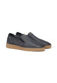 Zapatos oscuros de tela slip-on, hechos de cuero perforado, con paneles laterales elásticos y una suela de goma marrón clara.