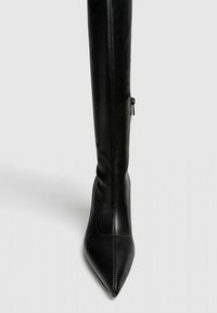 Czarne, sięgające za kolano szpilki wykonane z gładkiej skóry. Posiadają spiczasty czubek oraz boczny zamek błyskawiczny do zamykania.