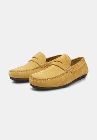Žute suède loafers cipele s ušivenim zaobljenim prstom, opremljene dekorativnom prednjom trakicom i ravnim gumeni đonom za udobnost.