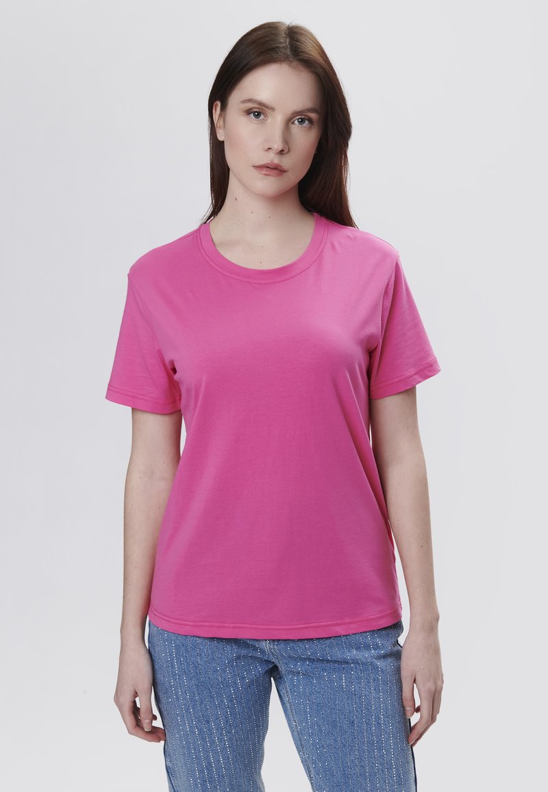 Lyserød bomulds t-shirt med rund halsudskæring og korte ærmer. Stoffet er glat med en løs pasform, parret med blå strukturerede jeans.