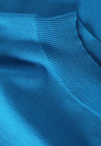 Helderblauwe sweaterstof met een gladde textuur, met een ribgebreide kraag en een naadloos ontwerp, dat de egale tint en kleurconsistentie benadrukt.