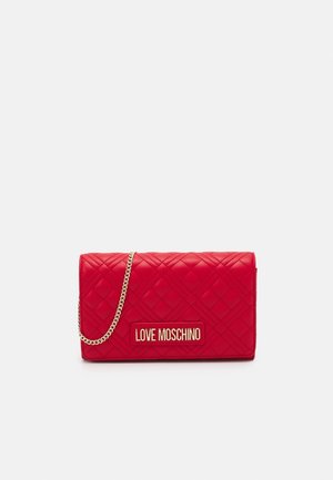Pochette en cuir matelassé rouge avec plaque logo dorée "LOVE MOSCHINO" et bandoulière chaîne dorée sur fond gris clair uni.