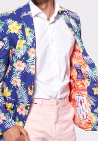 Marynarka w kwiatowy wzór w odcieniu niebieskim, z żółtymi i różowymi kwiatami. Wnętrze wyłożone pomarańczowym wzorem kwiatowym oraz grafiką deski surfingowej. Zapięcie na guziki.