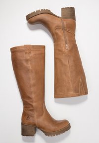 Botas altas hasta la rodilla de cuero marr�ón con un acabado texturizado, punta redonda, cremallera lateral y un tacón grueso de madera con suela dentada.