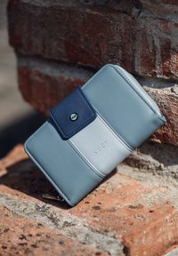 Tyrkysová kožená peněženka se tmavě modrou klopou a embosovaným logem "VUCH", se hladkým povrchem a zipovým uzávěrem.