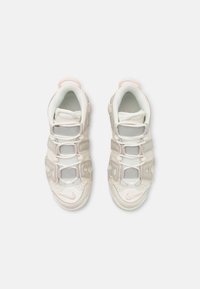 Chaussures de sport blanches et rose clair avec un dessus en maille, trois sangles Velcro et des motifs texturés sur les côtés.