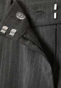 Tissu gris rayé avec un motif en chevrons, comprenant un bouton, des clips métalliques et une ouverture zippée. Texture lisse, design ajusté.