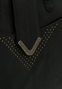 Zwarte leren handtas met een gestructureerd oppervlak, hardware van goudkleurig metaal en een decoratief patroon van nagels dat een V-vorm vormt.