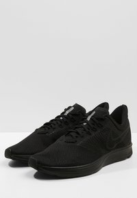 Baskets de sport noires en matériau mesh. Caractéristiques : design respirant, lacets plats et bout arrondi. Accents de branding subtils.