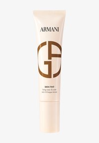 Armani Skin Tint i en beige klem tube med en blank finish. Har en fremtredende brun logo, merket for langvarig bruk og pleie.