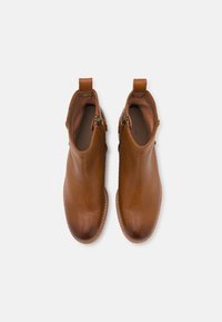 Botas de cuero marrón hasta el tobillo con una textura suave, cremalleras laterales, lengüetas y detalles cosidos alrededor de las suelas.