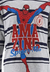 Graues Langarmshirt mit horizontalen marineblauen Streifen. Verziert mit einem Spider-Man-Graphic und kühnen roten Schriftzug "AMAZING Spider-Man."