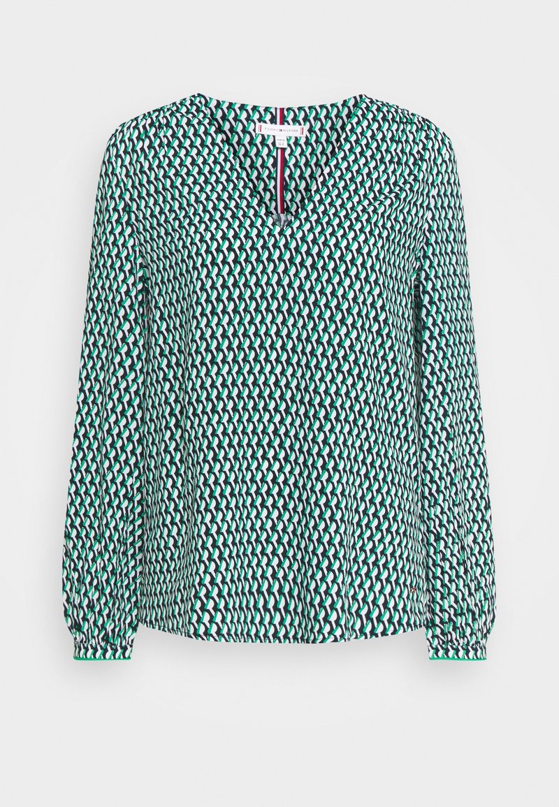 Blouse à manches longues avec motif géométrique vert, noir et blanc, col en V et poignets froncés.