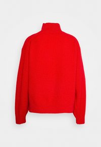 Pull en maille côtes rouge vif à manches longues et col montant, vu de dos sur fond blanc.