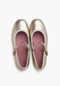 Ballet flats metallici dorati con interno rosa e cinturino elastico bianco. Texture liscia, punta arrotondata e design minimalista.