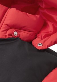 Giacca imbottita rossa e nera con una texture morbida, caratterizzata da dettagli in metallo argentato e un chiusura a bottone sul colletto. Design bicolore evidente.