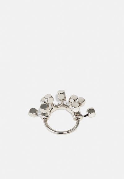 Bague en argent avec des blocs géométriques disposés sur le dessus, avec une finition métallique lisse et un design de bande ouverte.