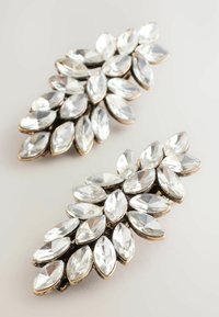 Două cercei ornamentați cu cristale clare tăiate în formă de marquise, grupate și montate pe metal de culoare auriu, pe un fundal alb.