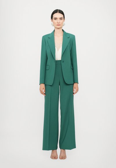 Grønn skreddersydd blazer og vide bukser, med en jevn tekstur, enkelt knapp og en lett cami under.