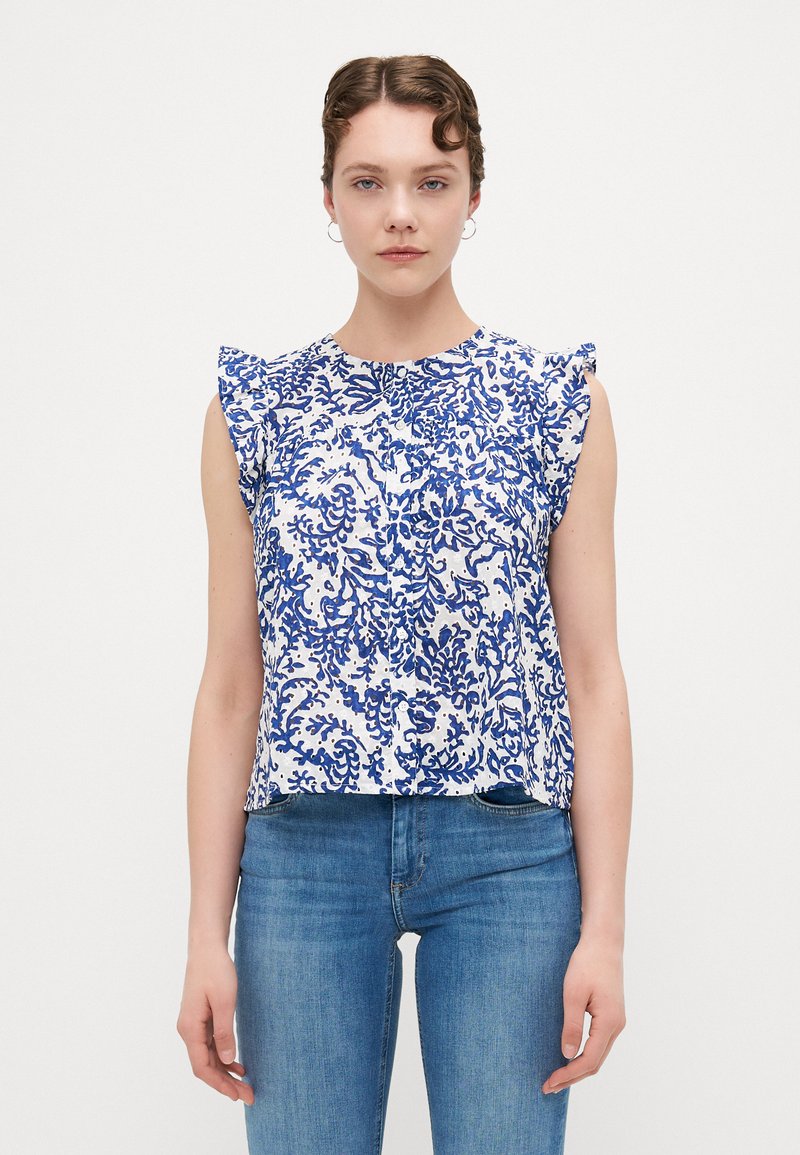 White blouse with blue floral pattern, ruffled sleeves, round neckline, and relaxed fit. Made from lightweight fabric.