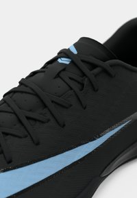Zwarte sport schoen met een tekstuur bovenkant, zwarte veters en een lichtblauwe accentstreep langs de zijkant. Beschikt over een duurzame rubberen zool.