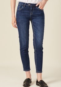 Tmavě modré skinny džíny vyrobené z denimové tkaniny, s klasickým designem pěti kapes, světlým švem a kovovým zapínáním na přední části.