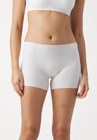 Bijele hipsterske kratke hlače napravljene od glatkog, rastezljivog materijala s elastičnom waistbandom, s nevidljivim dizajnom za udobnost i minimalnu vidljivost.