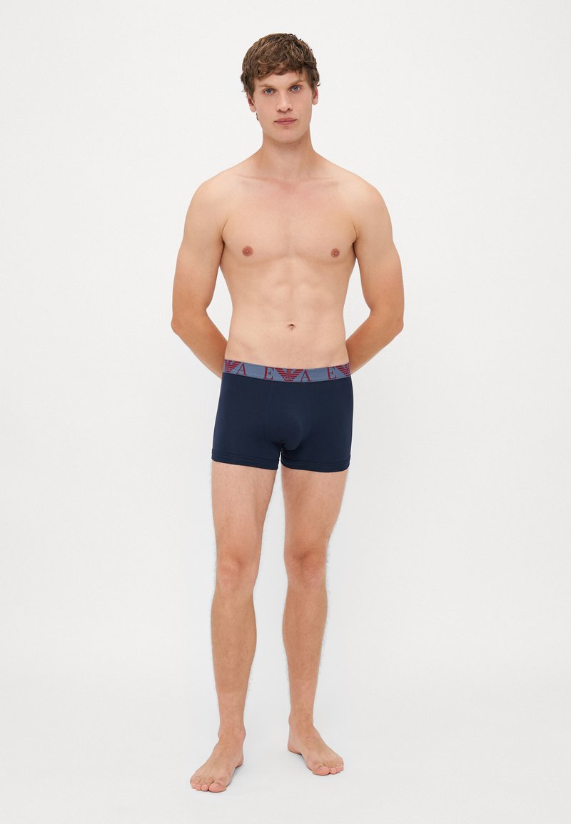 Marinefarbene Herren-Boxershorts mit eng anliegendem Schnitt, ausgestattet mit einem gemusterten, elastischen Bund in Burgunder und Grau. Weicher, glatter Stoff.