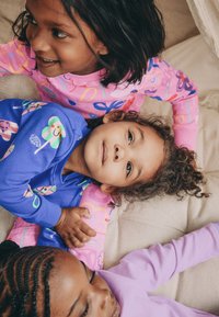 Kolm last värvilistes pidžaamades: üks roosas lõbusate mustritega, teine sinises põnevate kujundustega ja kolmas helesinisel.