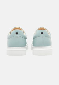 Scarpe in pelle verde menta con finitura liscia, suola in gomma bianca e tacco arrotondato. Presentano un discreto logo nero sul retro.