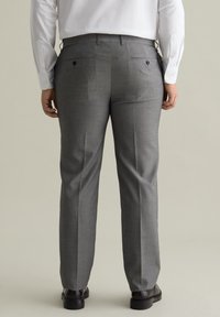Grijze slim-fit broek met een soepele textuur, voorzien van twee achterzakken en een rechte pijp, gecombineerd met zwarte schoenen.