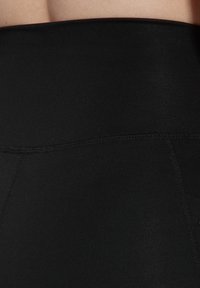 Zwarte high-waisted leggings met een soepele elastische tailleband en flatlockstiksels voor verbeterd comfort en duurzaamheid.