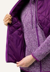 Lila gesteppte Jacke mit glattem Innenfutter. Verfügt über eine strukturierte äußere Schicht in einem helleren Lila und eine mit Reißverschluss versehenen Tasche auf der Innenseite.