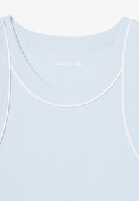 Top de tirantes acanalado de color azul claro con ribetes blancos. Presenta un escote redondeado y el logotipo de la marca impreso en el interior. Tela de mezcla de algodón suave y elástica.