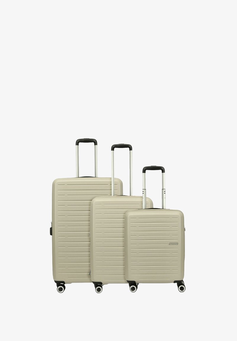 Trois valises rigides beiges de tailles variées avec des motifs rayés texturés, des poignées noires et des roues pour la mobilité.